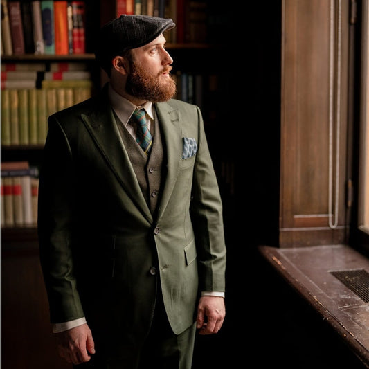  A distinguished man in a bespoke three-piece suit by THOR, tailored in Portland, OR. The olive-green ensemble, complete with a waistcoat, exemplifies the craftsmanship of THOR's custom tailoring.